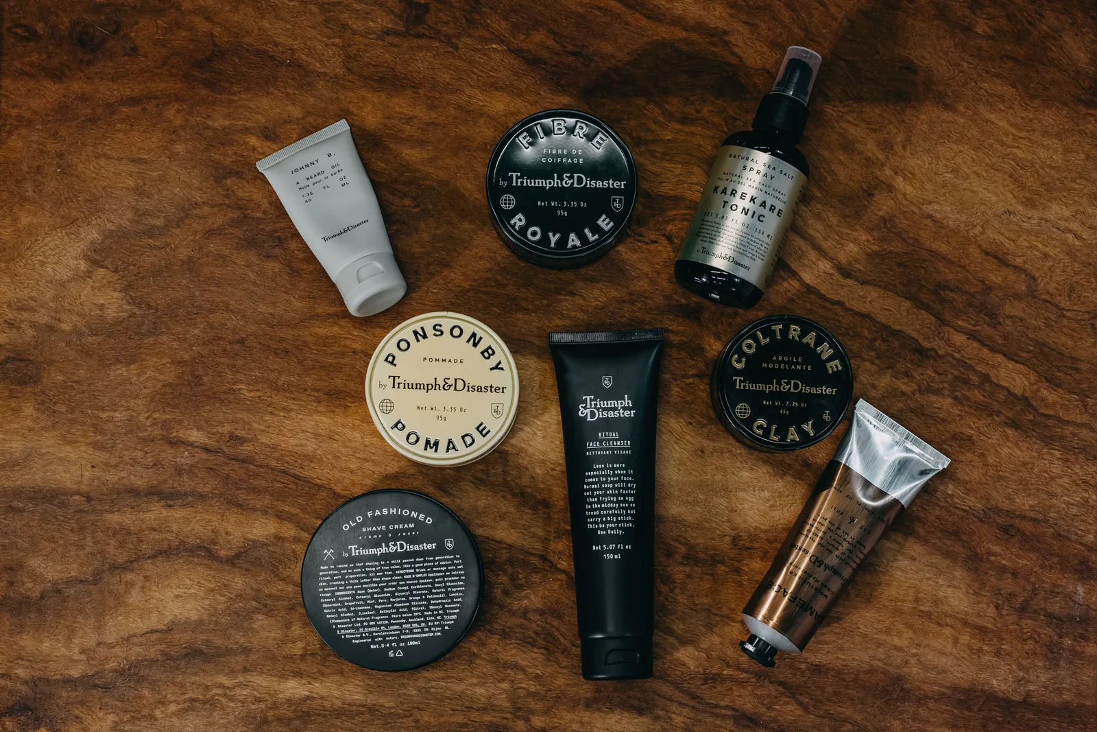 Shave cream, beard oil and pomade laid out on the timber counter at The Two Georges