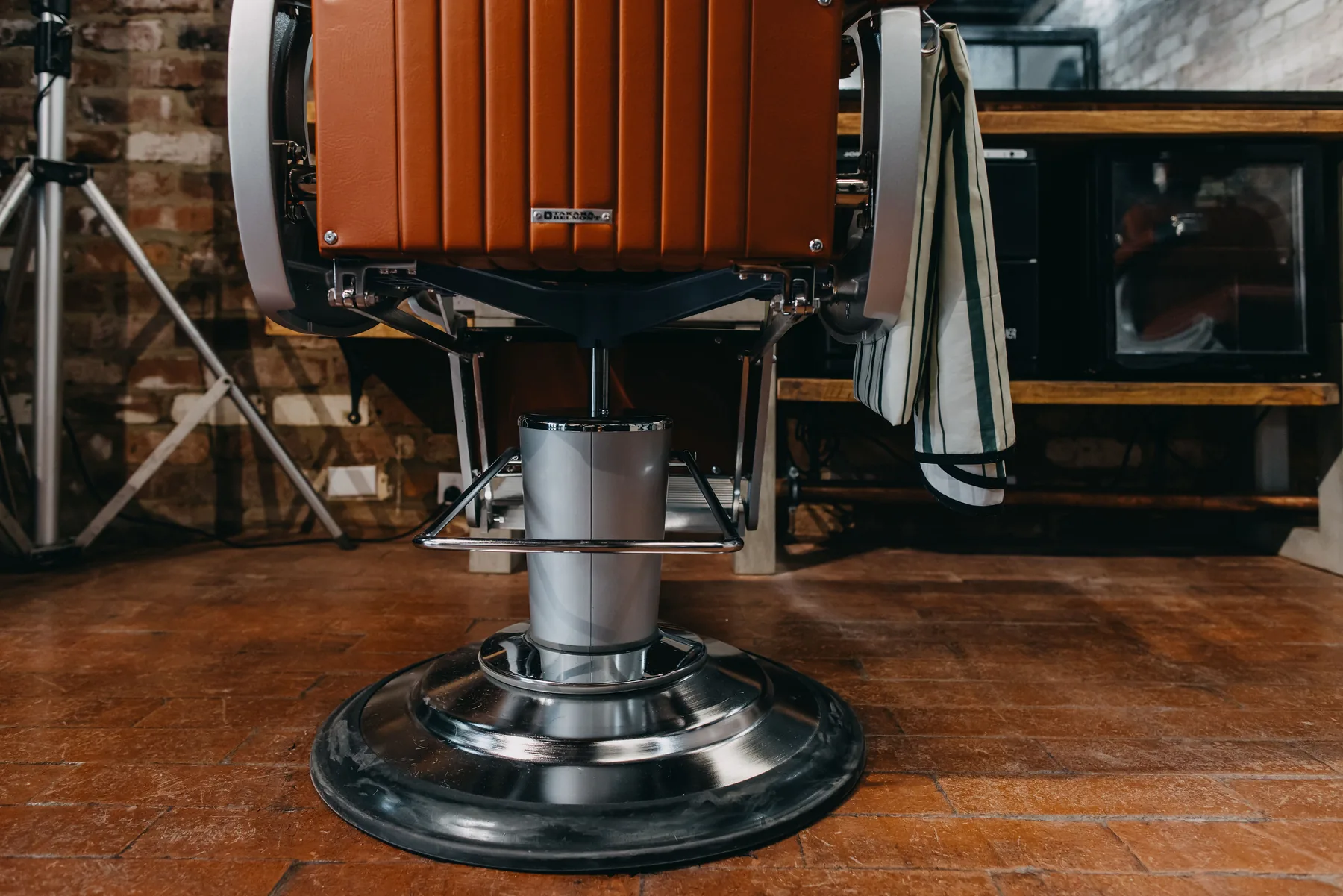 The chrome pedestal of a restored barber chair on the brick floor at The Two Georges