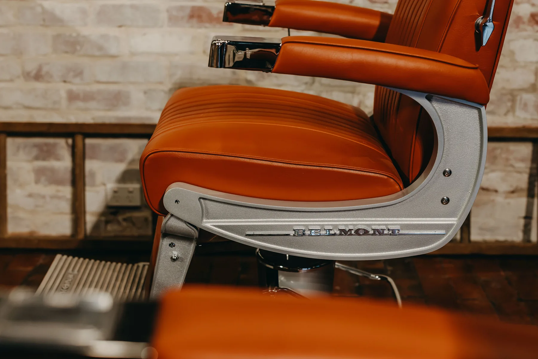 The polished arm of a restored tan leather Belmont barber chair at The Two Georges